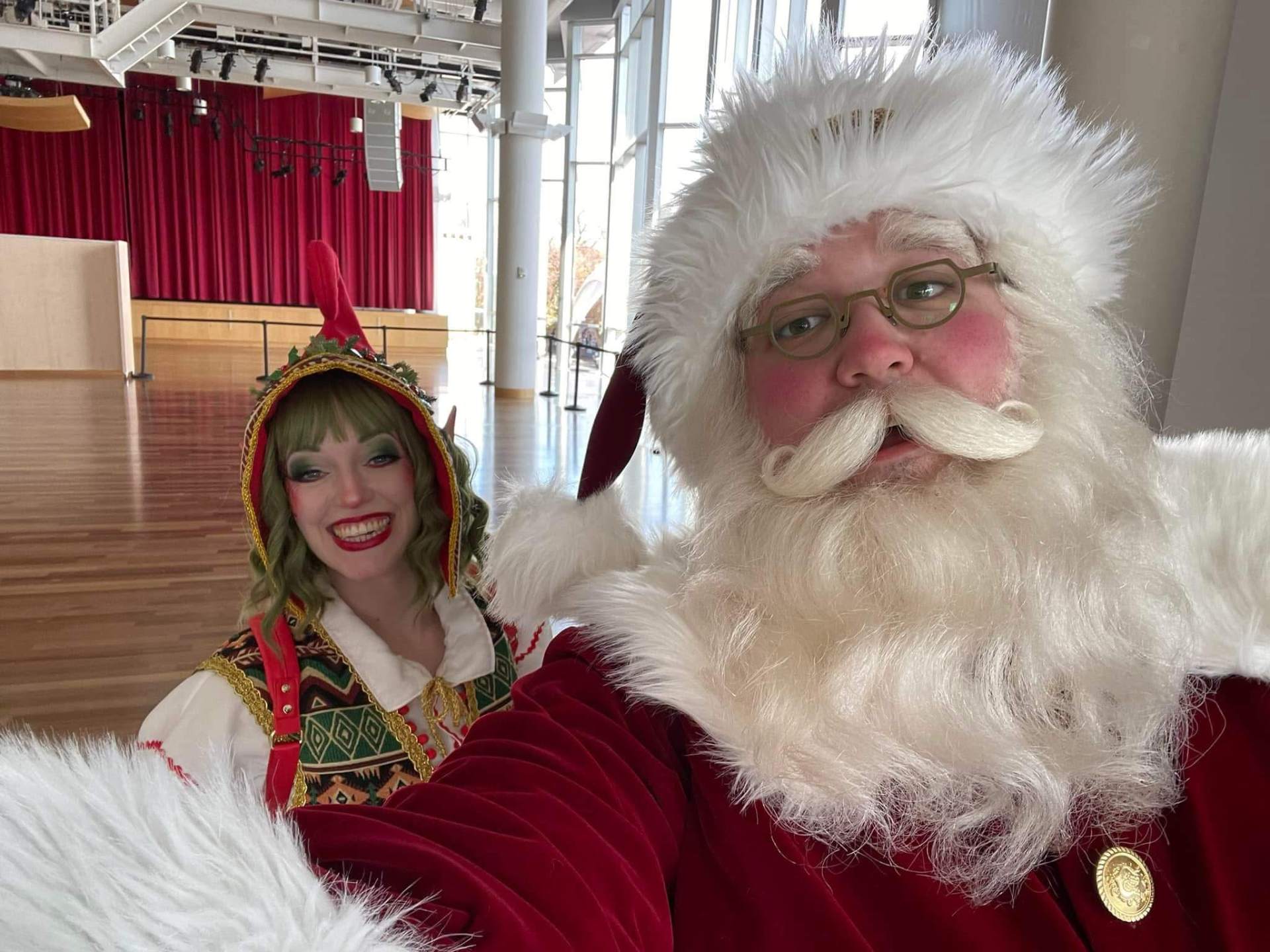 Santa and his elf taking a selfie at an event hall