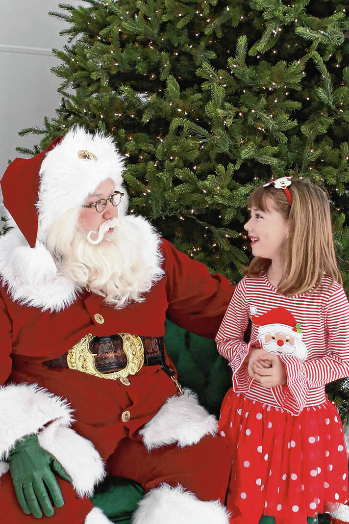 Santa chatting with a little girl by the Christmas tree