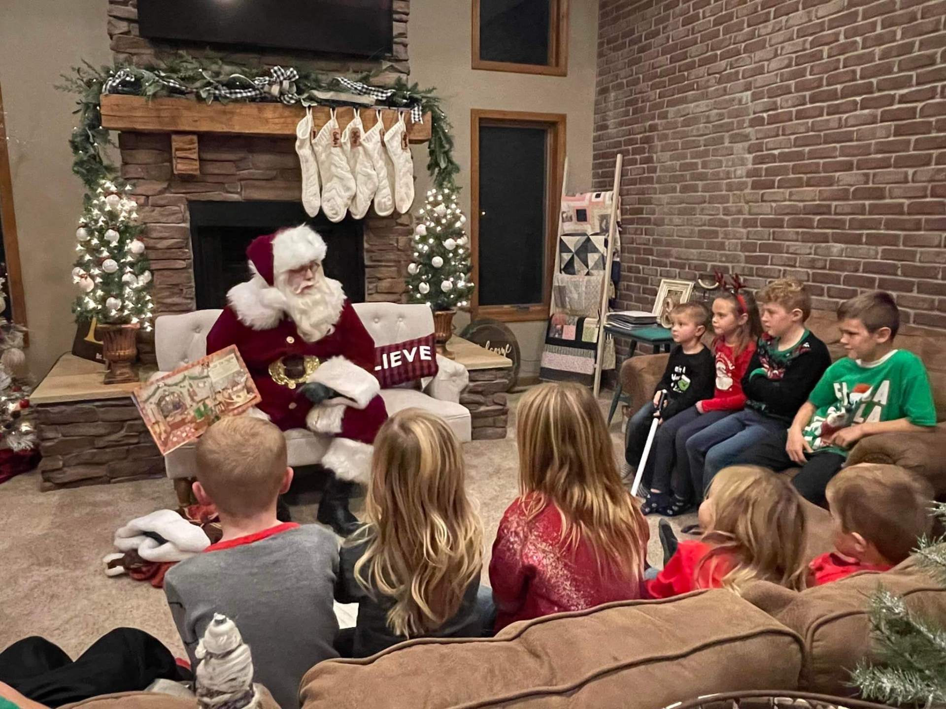 Santa reading a storybook to a circle of children at a family home visit