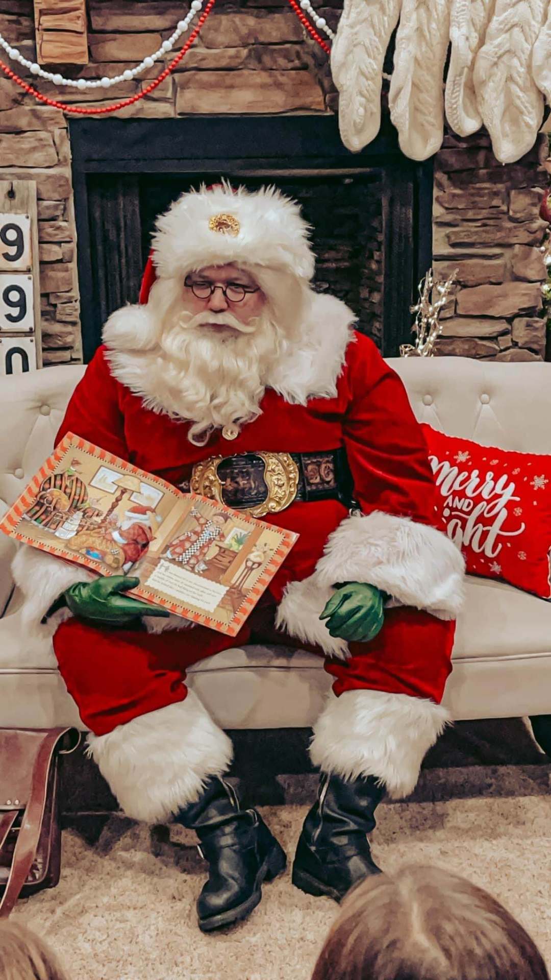 Santa reading a Christmas storybook by the fireplace