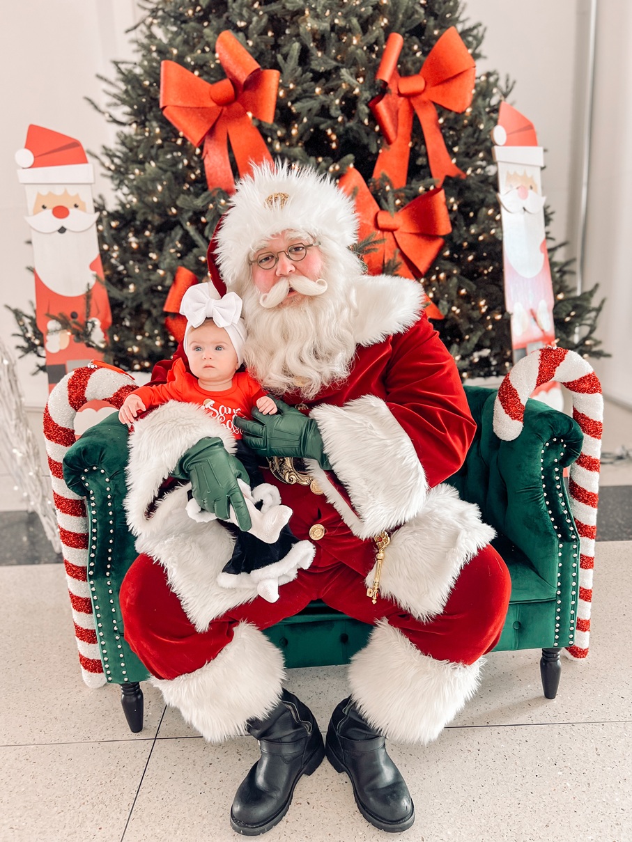 Santa cradling a baby girl on a green velvet chair