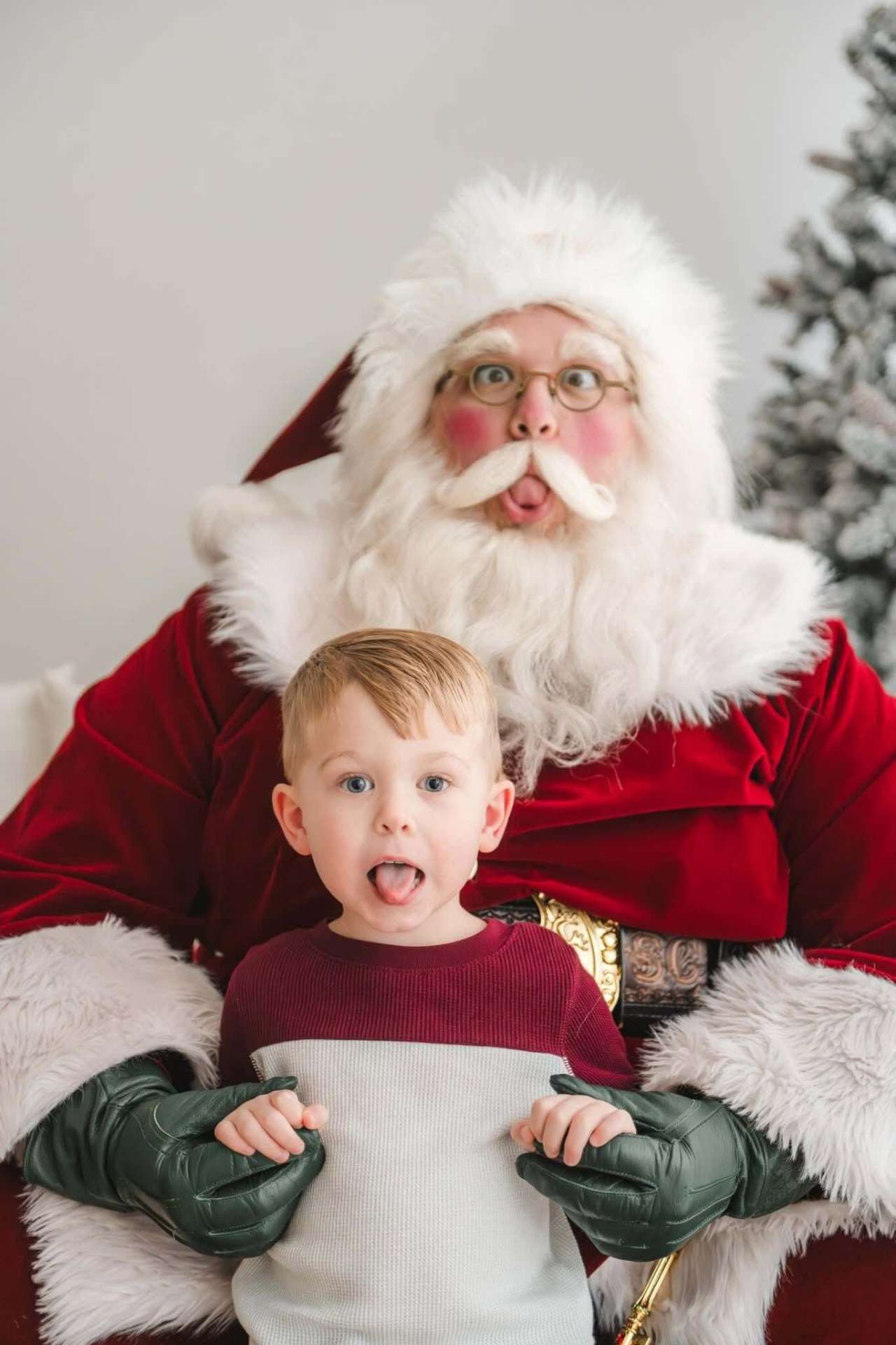 Santa pulling a silly face with a wide-eyed young boy
