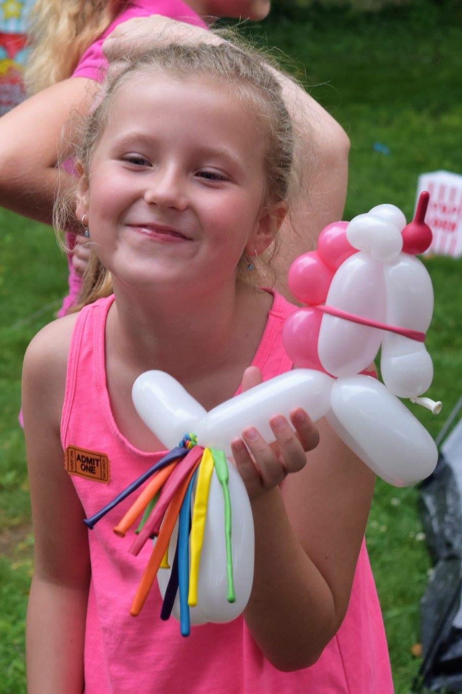 Smiling girl with a white and pink balloon poodle