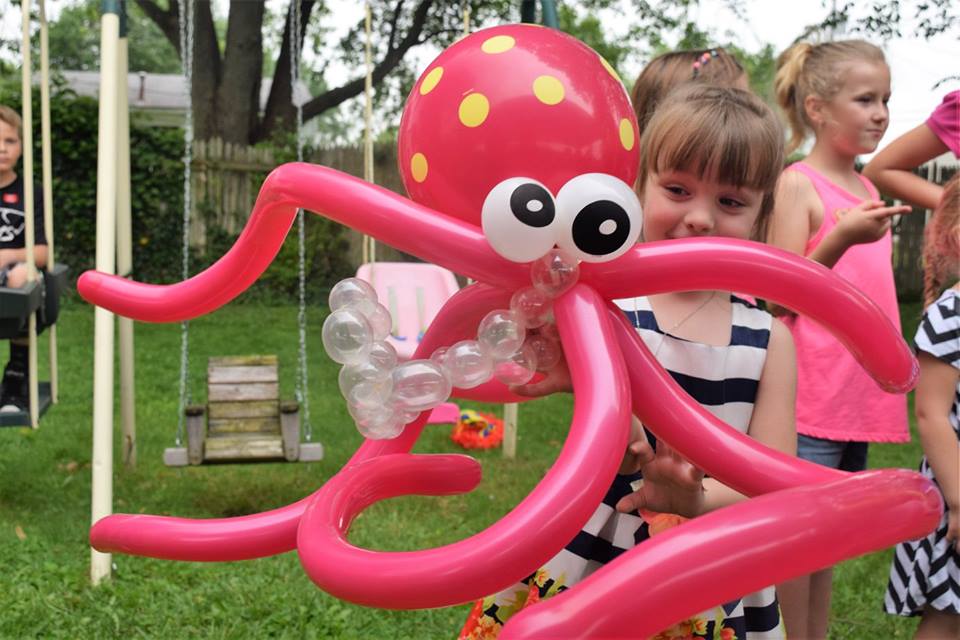 Child posing with a giant pink balloon octopus